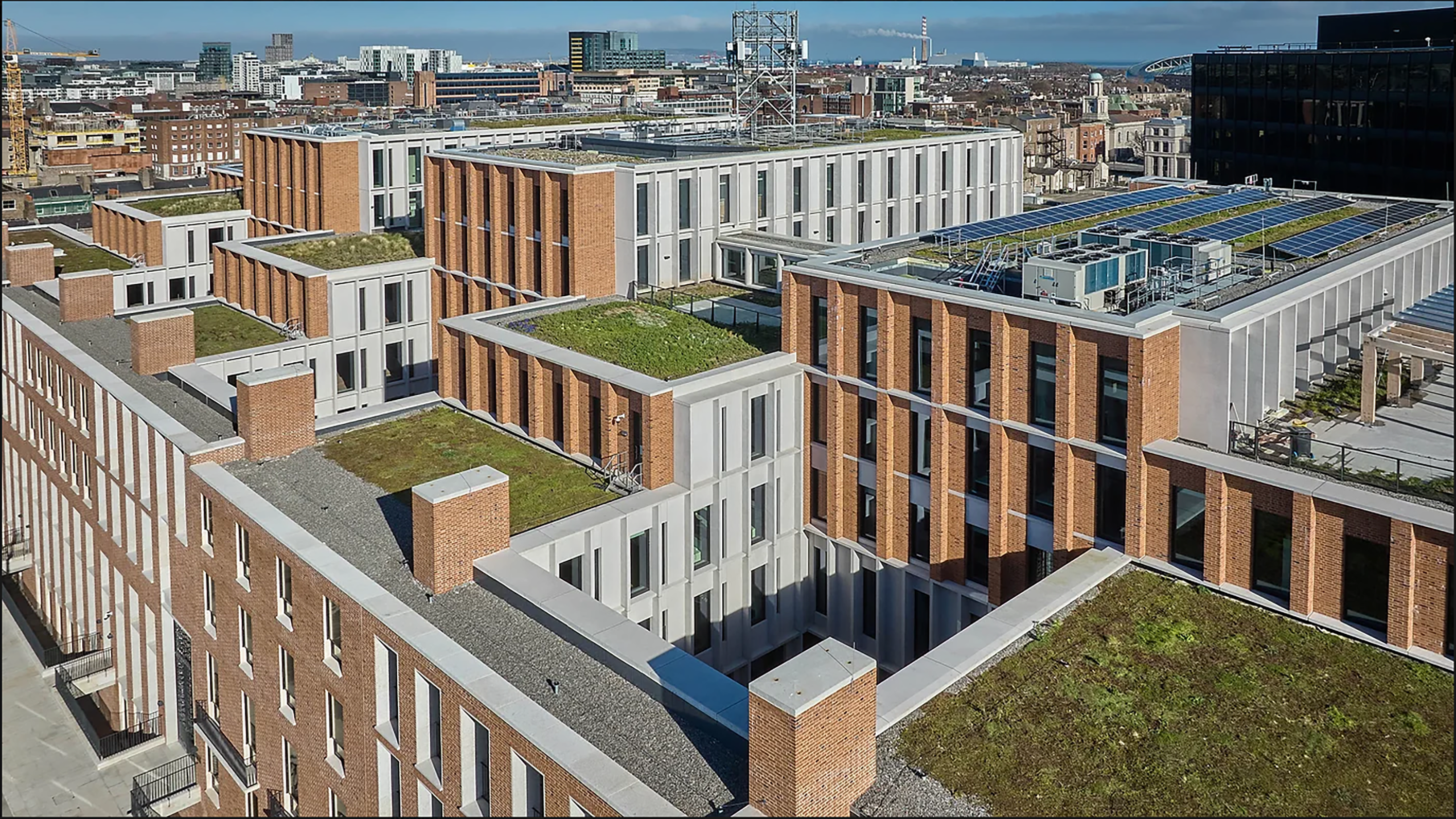 Aerial shot of a modern city office block, with green grass and solar panels on the roof