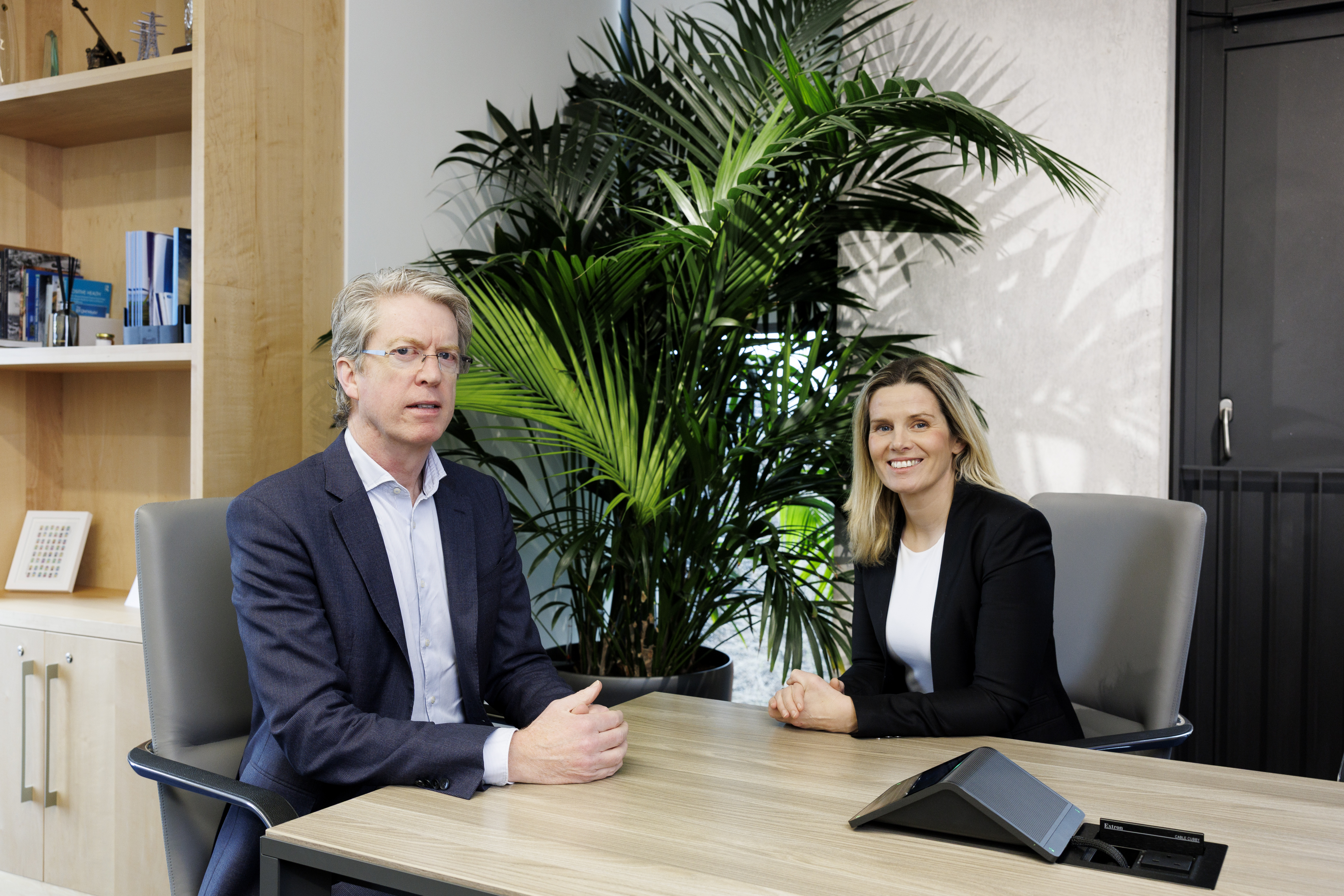 Man and woman sitting at office table in business attire 