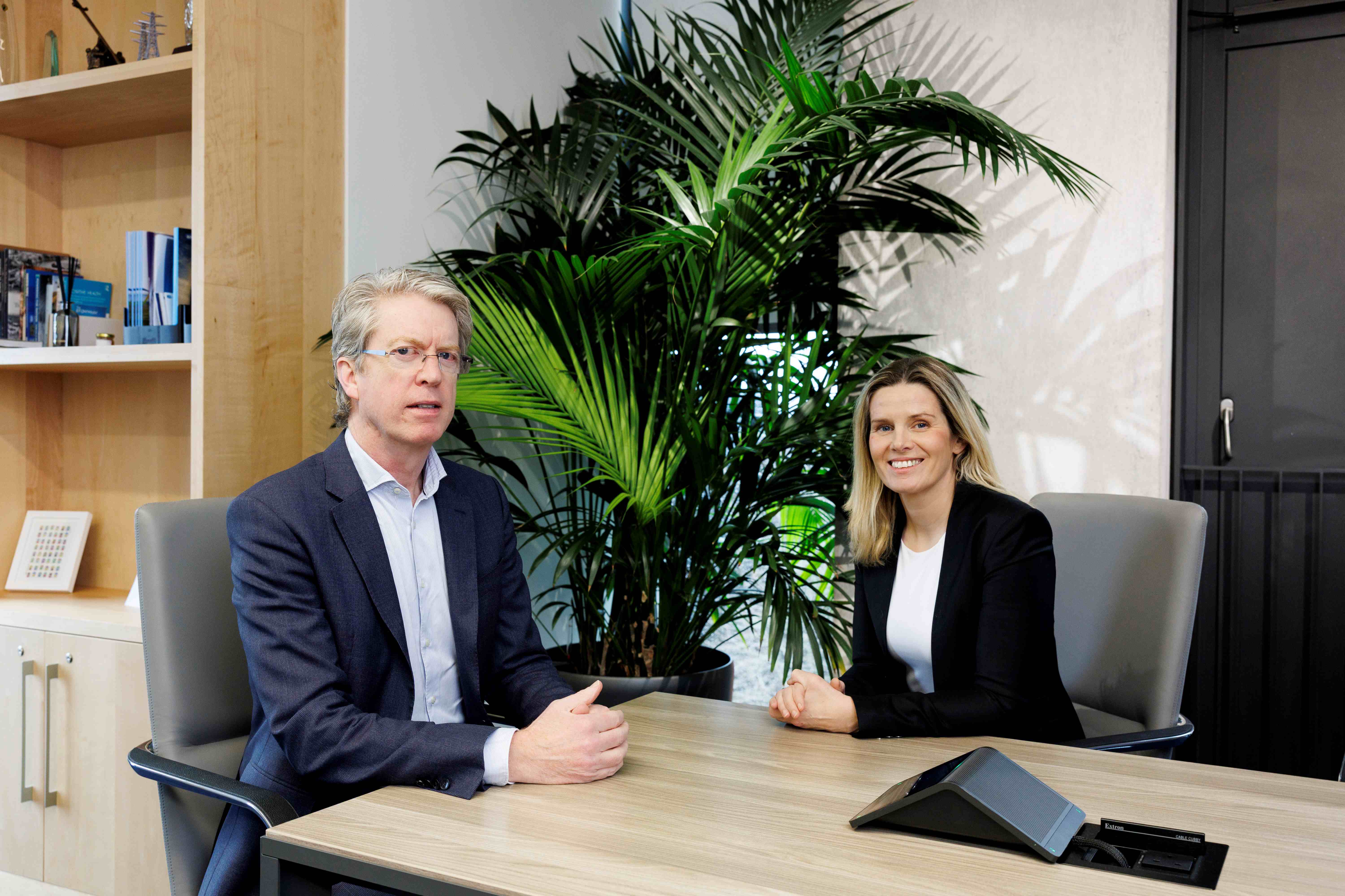 Picture of man and woman sitting in an office in business attire