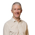 White man with grey hair and wearing a little beige shirt