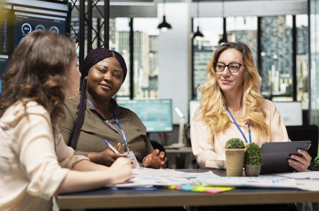 Colleagues collaborating around a table during a meeting in a modern office workspace.
