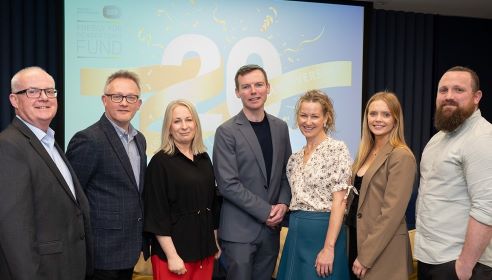 Group of seven people standing at an event in front of a screen with the number 20 on it