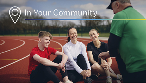 Shot of three young people and coach at an athletics track, with the superimposed words 'In Your Community'