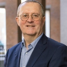 Michael Barry, white man with grey hair, framed glassed wearing blue jacket and light blue shirt