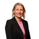 White woman with long blonde hair and wearing a black jacket and pink jumper