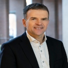 Pat Fenlon, white man with black hair and wearing white shirt and black jacket