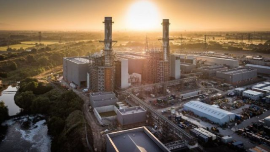 Drone image of a large combined gas generation plant against the backdrop of sunset and other buildings around it