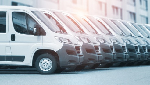 A row of white vans in front of a building