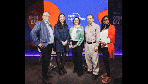 Five people standing in front of a blue and orange Free Electrons branded screen including two men and three women