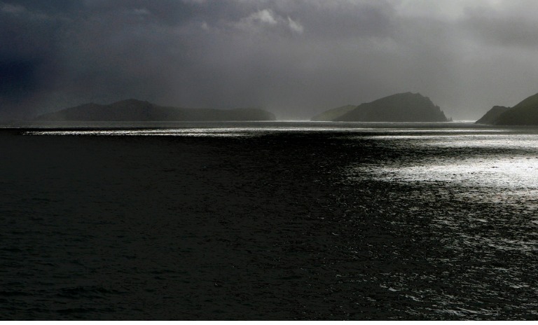 Picture of an island and sea surrounded by dark clouds