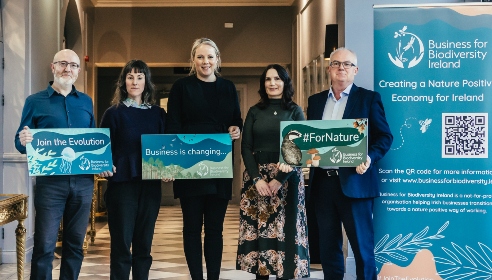 Five people standing in a row with three holding placards with Business for Biodiversity wrote on them.