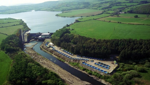 A drone image of hydro station surrounded by rivers and green grass and trees