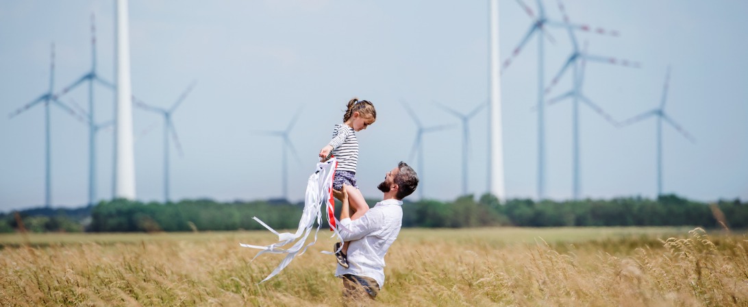 mature-father-with-small-daughter-standing-on-field-on-wind-farm