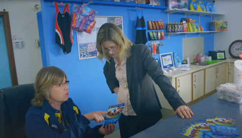 Two women chatting and looking at a piece of paper in an office