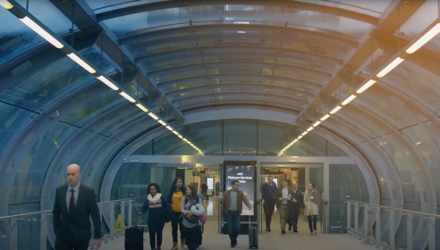 A terminal building with people walking through with suitcases