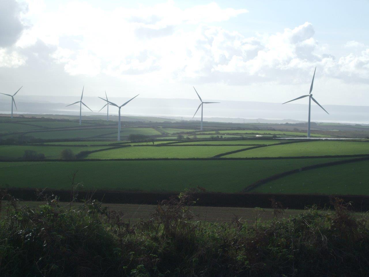 Six wind turbines standing erect on a large green site